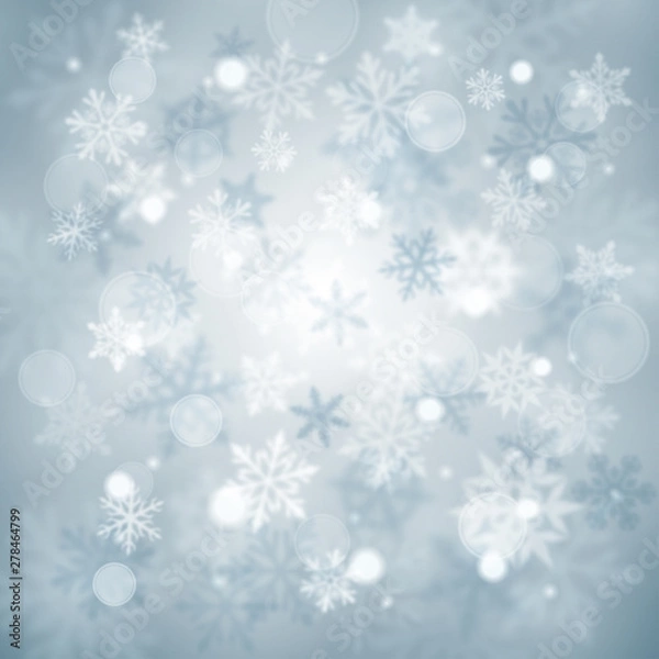 Fototapeta Christmas blurred background of complex defocused big and small falling snowflakes in light blue colors with bokeh effect