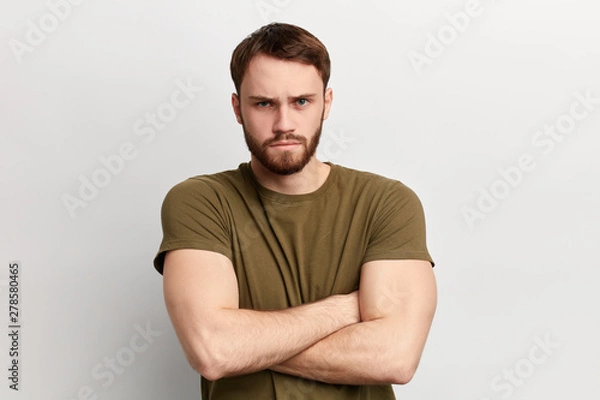 Fototapeta angry sad unhappy serious man with disapproving expression on face and crossed arms looking at the camera. close up portrait. isolated white background. negative emotion
