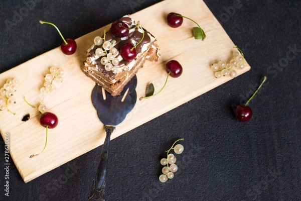 Fototapeta Top view of a slide of chocolate cake with a cherry on a black background