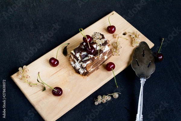 Fototapeta Top view of a slide of chocolate cake with a cherry on a black background