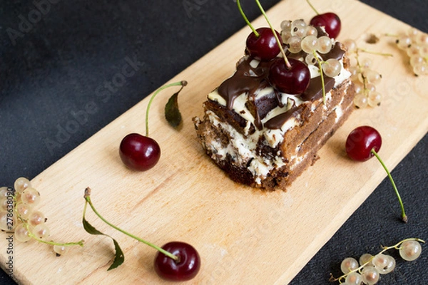 Fototapeta Top view of a slide of chocolate cake with a cherry on a black background