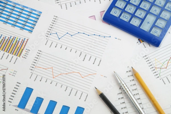 Fototapeta Business concept, calculator, silver pen and pencils on financial charts and graphs