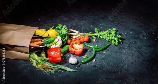 Fototapeta Healthy food in full paper bag of different products vegetables and fruits on dark background
