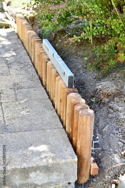 Obraz Exchanging the finished new curb next to the pavement  instead of the old curb in our garden