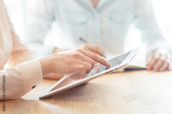 Fototapeta Hipster girl touching with finger on mock up display of modern touch pad connected to free 4G internet connection.Cropped view of woman's hands holding digital tablet with blank screen for website