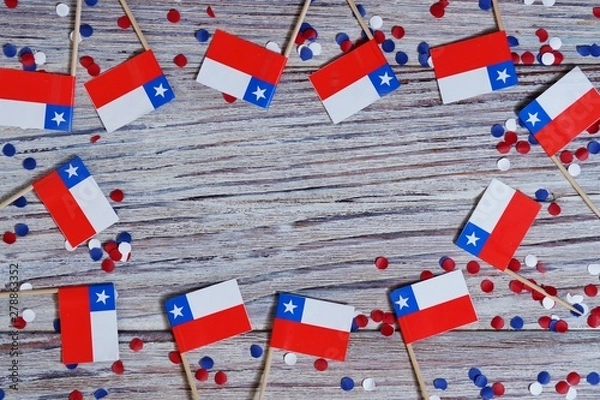 Fototapeta September 18, happy independence day of Chile. memorial day for independence. the concept of patriotism. mini flags with confetti on white wooden background
