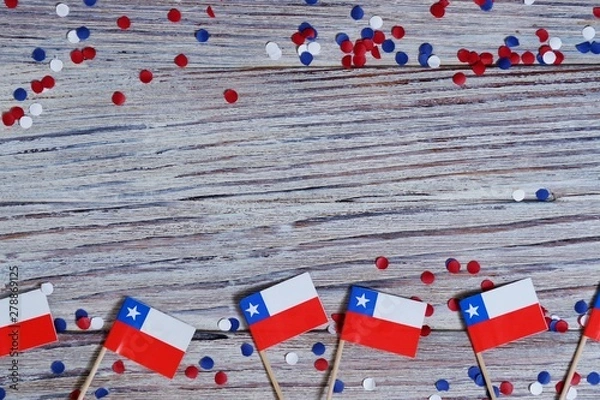 Fototapeta September 18, happy independence day of Chile. memorial day for independence. the concept of patriotism. mini flags with confetti on white wooden background