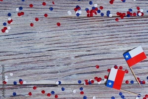 Fototapeta September 18, happy independence day of Chile. memorial day for independence. the concept of patriotism. mini flags with confetti on white wooden background