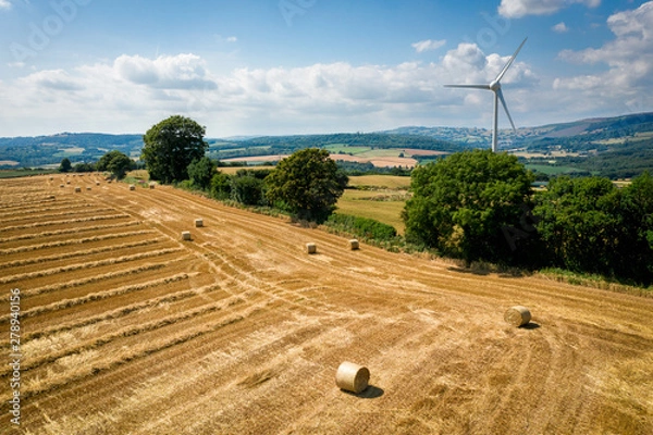 Fototapeta Aerial view of Straw bales with a wind turbine on farmland in Wales UK