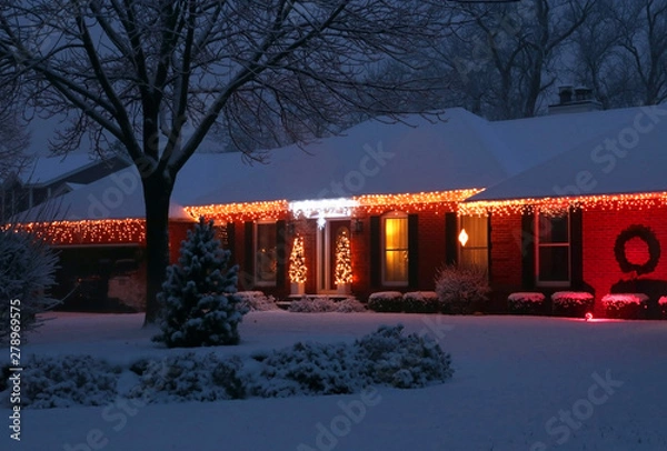 Obraz Beautiful winter blizzard evening view. Front yard of the private house covered by snow and decorated for winter holiday season glowing in the night. Christmas and New Year background.