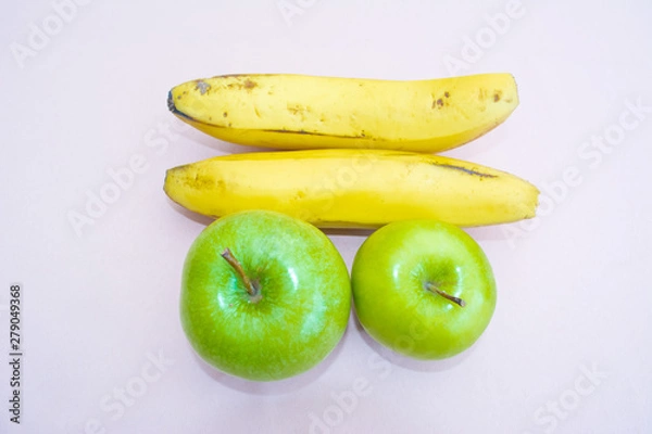 Fototapeta Two bananas next to two green apples with white background