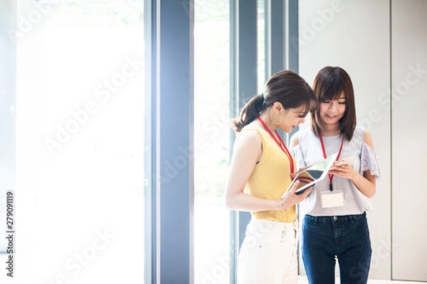 Fototapeta スマートフォンで情報を共有する女性達