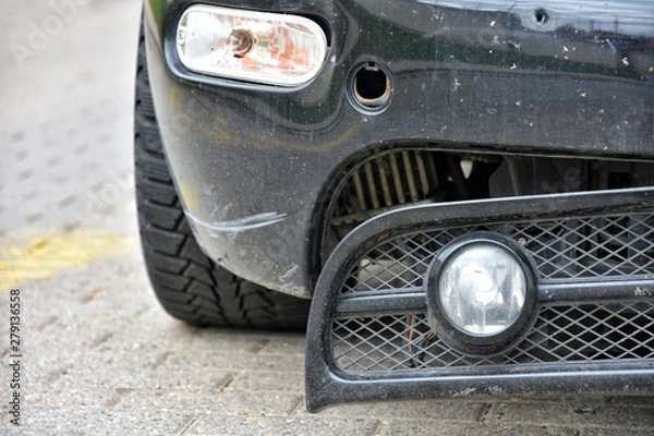 Fototapeta Road accident.  Black car with a broken bumper. Crushed automobile bumper. Parked auto with breakdown bumps and headlight. Car vandalism. 