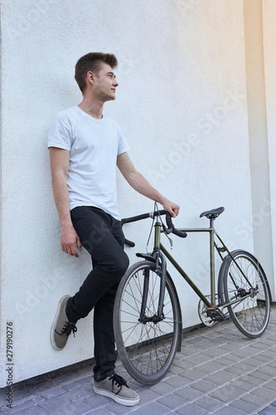 Fototapeta Handsome hipster man posing with bicycle in the city.
