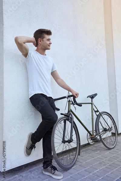 Fototapeta Handsome hipster man posing with bicycle in the city.