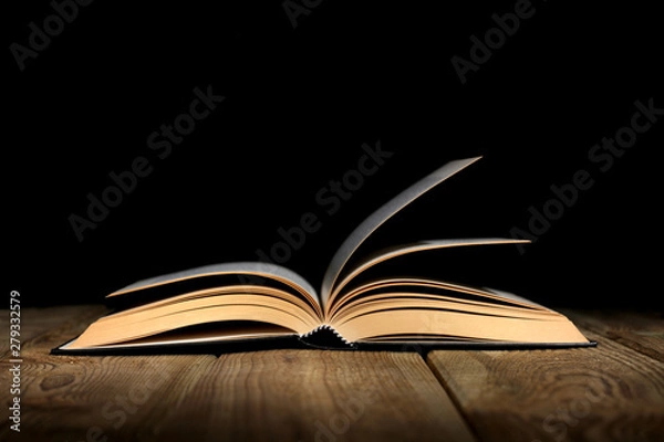 Obraz open book on a wooden table and black background  with copy space for your text