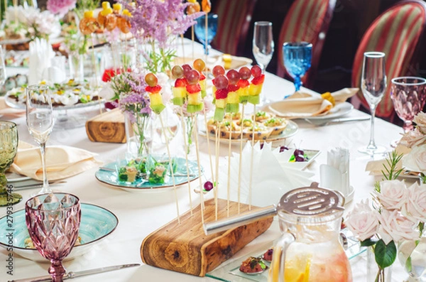 Obraz Assortment of canapes on wooden board. Banquet service with different food snacks and appetizers.. Catering food, snacks with strawberry, pineapple, fruit and berries. Party food concept.