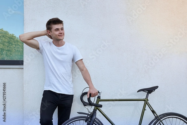 Fototapeta Handsome hipster man posing with bicycle in the city.
