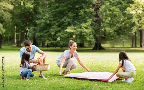 Fototapeta family, leisure and people concept - happy mother with daughter laying down picnic blanket on grass in summer park