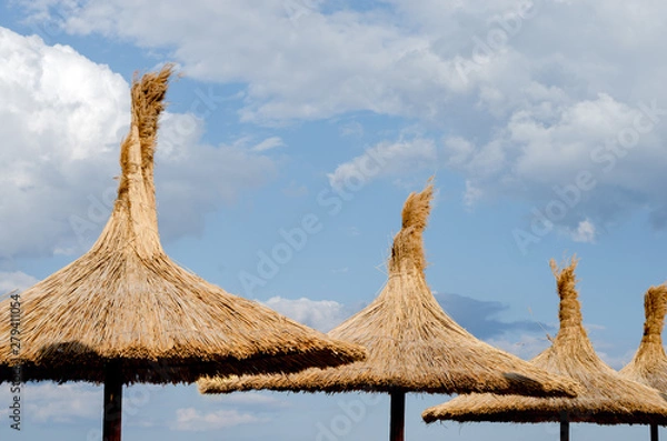 Obraz Reed umbrella roof against blue cloudy  sky  on  summer time   at beach .