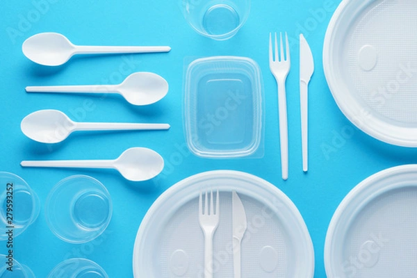 Fototapeta Various white plastic disposable tableware on blue background.