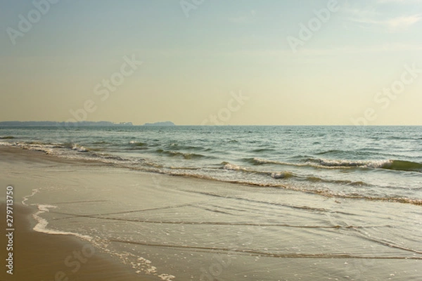 Fototapeta yellow sandy beach against the backdrop of the foam of the ocean waves under a clear sky