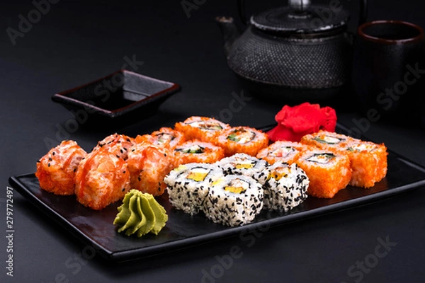 Obraz Close up rainbow Sushi Roll with salmon, eel, tuna, avocado, royal prawn, cream cheese Philadelphia, caviar tobica, chuka. Sushi menu. Japanese food and green tea teapot, copyspace.