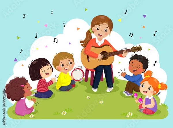 Obraz Young woman playing guitar with a group of kids singing and playing musical instruments. Female teacher and pupils having music in the park.