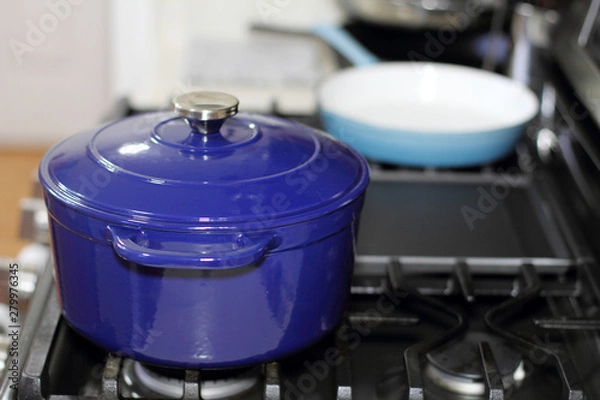 Fototapeta Porcelain enameled Dutch oven and skillet on the stove top in a home kitchen.