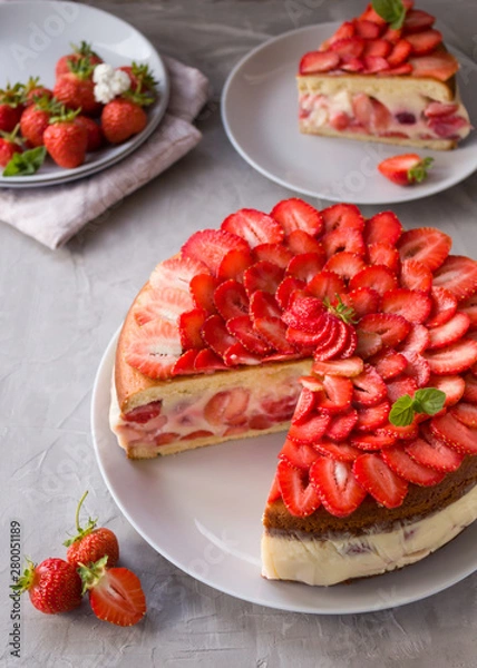 Obraz Cut biscuit cake with strawberries and vanilla jelly decorated with strawberry slices and mint leaves on a gray background. Fraisier cake .Vertical orientation, side view.