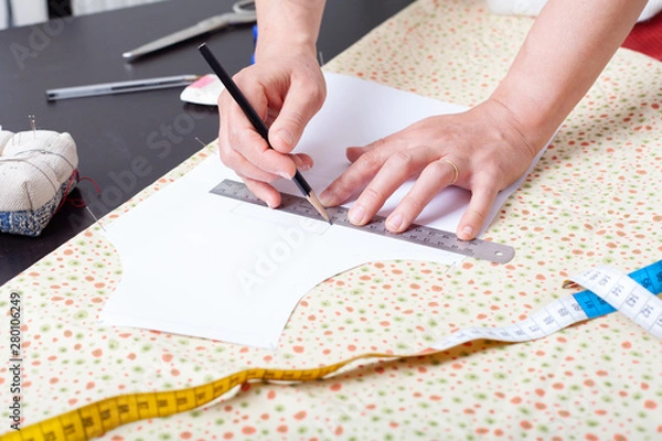Fototapeta Dressmaker at work, building patterns, hands, modeling, measuring, sewing machine