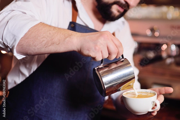 Fototapeta barista or coffee barman prepares coffee with a pattern on the foam or latte-art