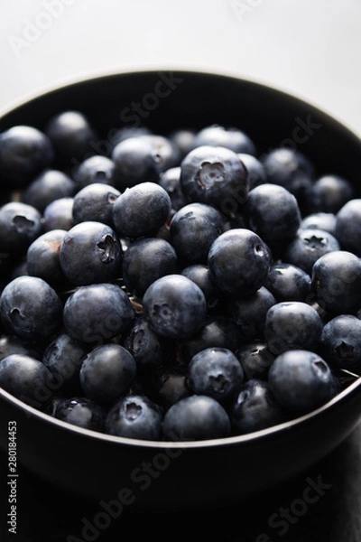 Fototapeta Freshly picked blueberries in black bowl on the table.