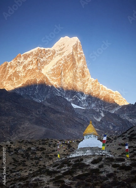 Fototapeta Stupa at sunrise near Dingboche village with prayer flags and mounts Kangtega and Thamserku, Nepal