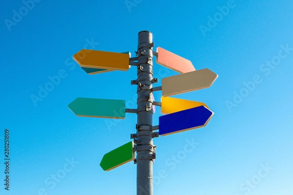 Obraz Guidepost with bright colored arrows against blue sky