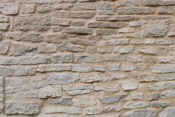 Fototapeta The texture of the fortress wall of hand-crafted bricks of gray limestone. Historical stonework of the Varangian fortresses