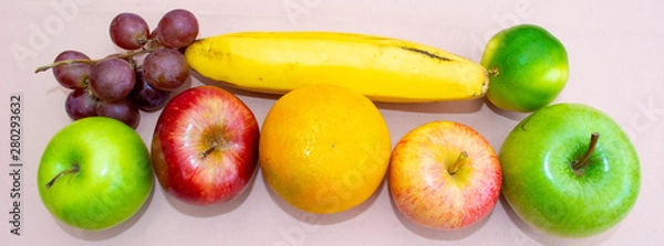 Fototapeta Colorful fruits in a row next to two bananas on the table