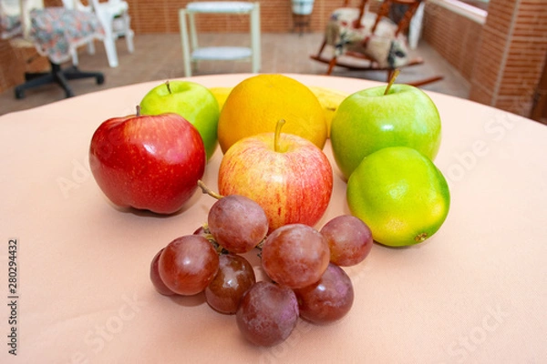Fototapeta Apples, grapes, orange and lemon located on the table