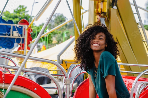 Obraz young girl of black color, laughing hair in ferris wheel, sitting enjoying a summer day, lifestyle portrait