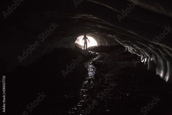 Fototapeta Silhouette of a man in the ice tunnel. Light from behind. Landmannalaugar trek, ice cave, Iceland