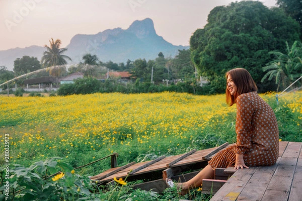 Obraz Happy beautiful freedom woman enjoying nature view on wooden bridge with yellow cosmos flower field alone, lifestyle and nature concept