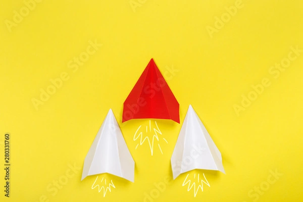 Fototapeta Group of white paper plane in one direction and one yellow paper plane pointing in different way on blue background. Business for innovative