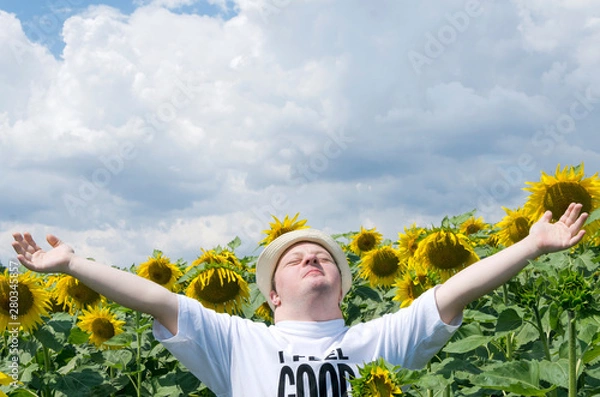 Fototapeta Young man standing with arms wide open in the sunflower field. Happy man with down syndrome in the countryside