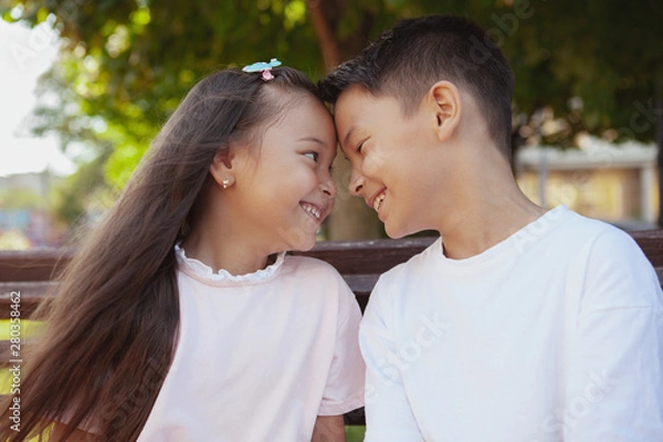 Obraz Close up of happy cute little kids smiling, touching with their foreheads. Adorable Asian brother and sister cuddling outdoors. Happy healthy kids having fun in the park