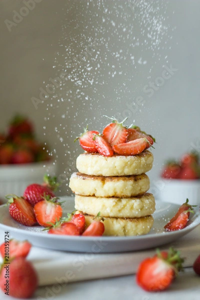 Fototapeta Cottage cheese pancakes syrniki with strawberrys. Powdered sugar pours. Delicious healthy summer Breakfast. Copy space, side view.