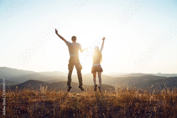 Obraz A young couple jumping and having fun. Dawn in the mountains, the beginning of a new day