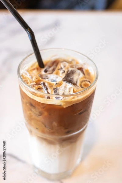 Fototapeta Iced coffee glass with black straw on table in cafe and restaurant.