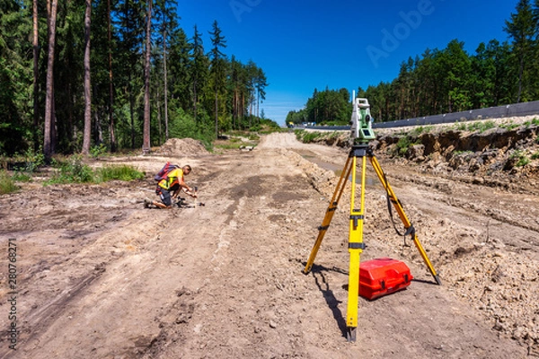 Fototapeta Surveyor engineer (worker) with equipment (theodolite or total positioning station) on the construction site of the road or highway