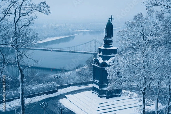 Fototapeta Illuminated bronze statue of Saint Volodymyr in winter Kyiv. Frosted Dnieper river and foot bridge at background. Ukraine