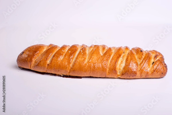 Fototapeta Dessert in the form of a poppy seed roll on a white background. Tasty golden pastry